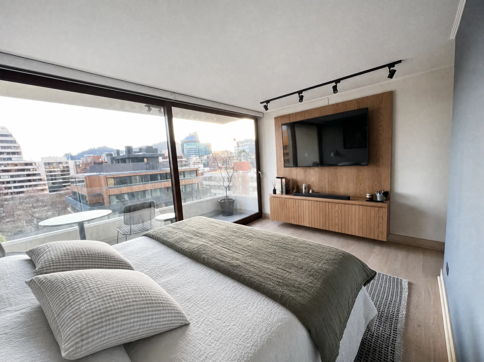 Dormitorio con panel de TV en madera y salida a balcón