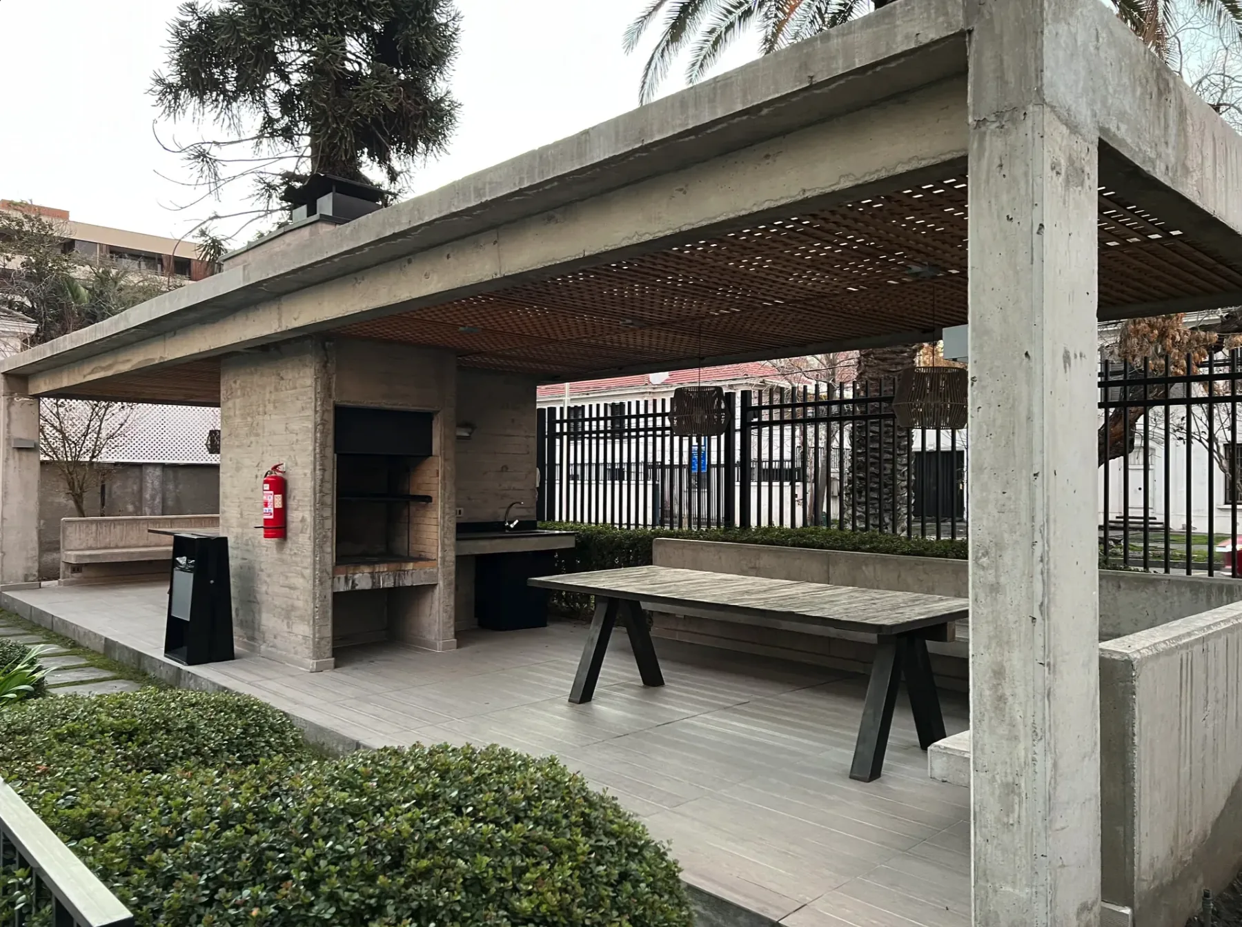 Pérgola de hormigón con quincho y comedor al aire libre